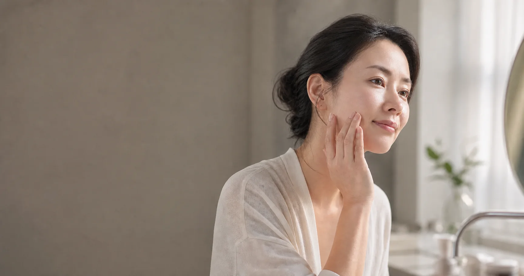 거울 앞에서 피부 상태를 살피는 30대 후반 여성
